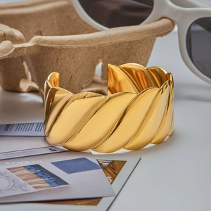 Detailed shot of a gold-plated striped wide cuff bracelet styled with elegant lifestyle props
