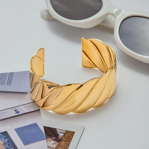 Macro detail of 18K gold plated croissant style textured bangle with high polish finish