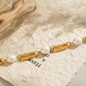 Détail d'un bracelet en acier inoxydable plaqué or 18 carats avec perles sur papier texturé