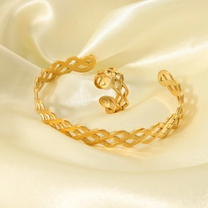 Detail view of gold wave pattern bangle and ring set on elegant silk fabric background