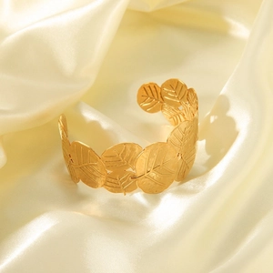 Close-up of golden leaf-shaped open cuff bracelet with delicate vein texture on silk