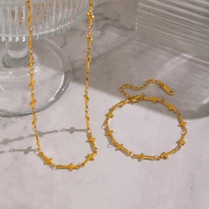Gros plan sur l'ensemble collier et bracelet croix plaqué or 18 carats sur marbre
