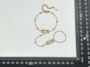 Détail de bracelet bague en acier doré avec pendentifs ovales sertis de zircons cubiques