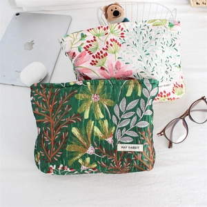 Detail of floral embroidery on quilted canvas makeup bags in green and pink colors