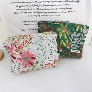 Detail of floral quilted makeup bags in pink and dark green with woven logo label