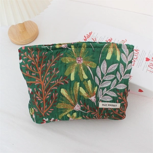 Detail of green quilted makeup bag with vintage floral patterns and brand label