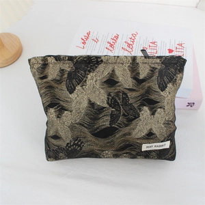 Close-up of vintage black and gold jacquard makeup bag with butterfly motifs and May Rabbit label