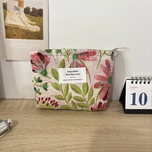 Detail of floral jacquard makeup bag with pink fabric and green leaf embroidery