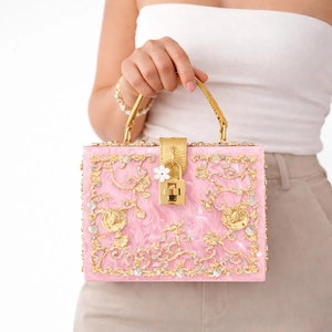 Elegant pink acrylic evening bag with gold hollow floral carving and rhinestone details
