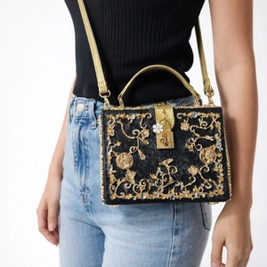 Close-up of luxury black acrylic evening bag with gold floral hollow carving and crystals