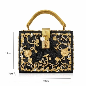 Detailed view of luxury black acrylic evening bag with gold hollow carvings and crystals