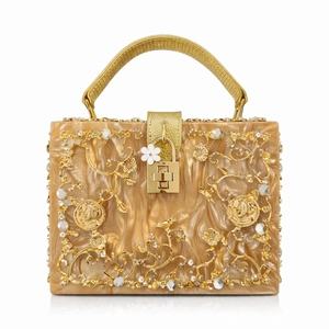 Macro shot of gold hollow-out floral carving and rhinestones on marble acrylic clutch bag