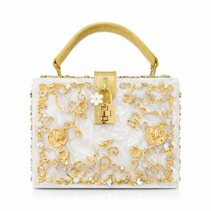 Macro view of baroque hollow metal filigree and sparkling crystals on acrylic evening bag