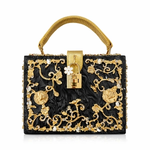 Macro detail of luxury black acrylic bag with gold floral cutout and crystal inlay