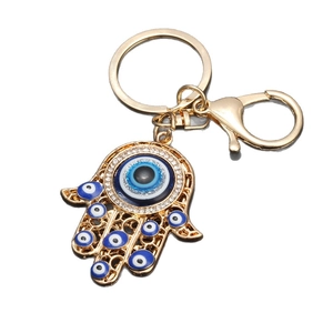 Golden Hamsa hand keychain with blue evil eye charms and sparkling crystals on white background