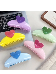 Macro shot of large candy-colored hair claws with heart designs and glossy finish