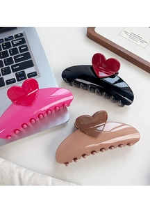 Detailed view of large glossy heart hair claws in pink, black, and khaki colors