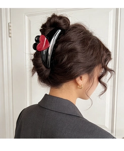Detail of black heart claw clip styled on brunette hair for a minimalist hair accessory look