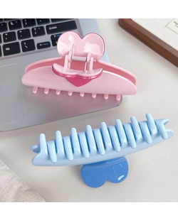 Pink and blue heart-shaped hair claw clips shown in a natural office desk setting