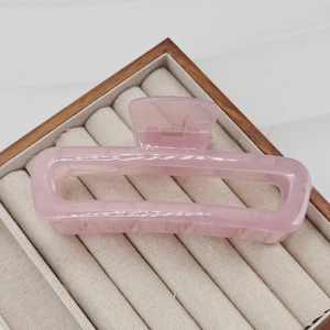 Detail of a 13cm translucent pink resin hair claw clip with pearlescent texture on a tray