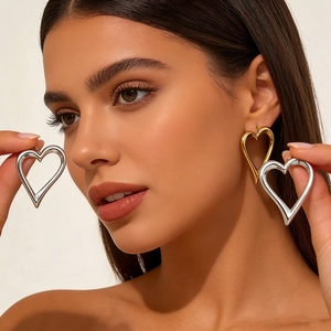 Chic oversized hollow heart stud earrings in polished gold metal shown on a model