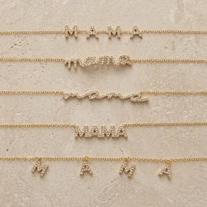 Five gold stainless steel MAMA letter necklaces with zircon stones on stone background