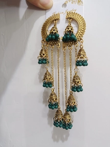 Detail of vintage bohemian Jhumka earrings with gold tassels and green beads