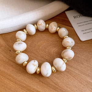 Crémefarbenes Acryl-Perlenarmband mit Marmormuster und goldenen Zwischenperlen