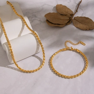 Set elegante con collana e bracciale a catena ritorta in acciaio al titanio dorato su marmo