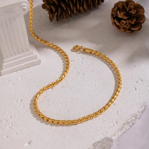 Dettaglio di una collana a catena attorcigliata in acciaio inossidabile dorato con chiusura