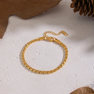 Dettaglio di un bracciale a catena ritorta dorata con chiusura a moschettone e catena