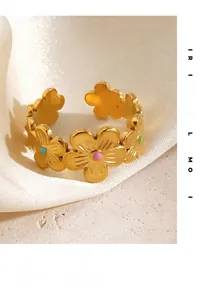 Detailed close-up of gold daisy rings with colorful enamel on soft white silk fabric