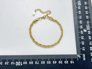 Détail d'un bracelet chaîne torsadée dorée montrant le fermoir mousqueton et les mesures réelles