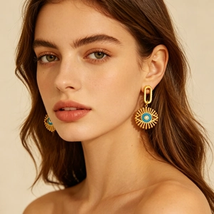 Boucles d'oreilles pendantes œil grec dorées avec incrustation bleue et détails texturés