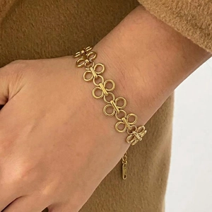 Gold stainless steel infinity link bracelet worn by model over a camel wool coat