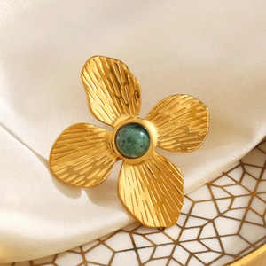 Golden brushed flower ring with green natural stone on elegant satin background
