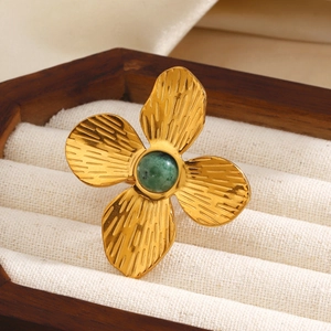 Golden flower ring with green stone on white velvet inside a luxury wood box