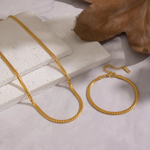 Luxurious gold stainless steel snake chain necklace and bracelet set on stone decor