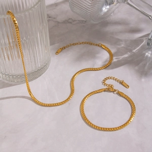 Detailed view of golden snake bone necklace and bracelet set on marble surface