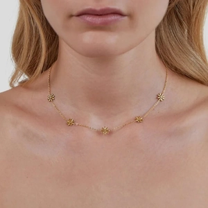 Elegante collana con margherite in acciaio al titanio dorato indossata per un look raffinato