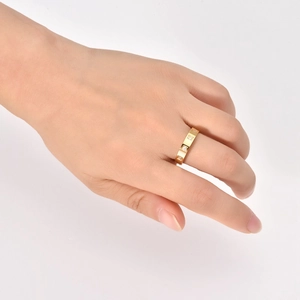 Detailed view of 18K gold band ring with geometric square pattern and tiny diamonds