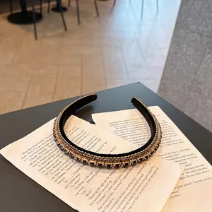 Close-up of a vintage headband with black crystals and gold chain on old paper