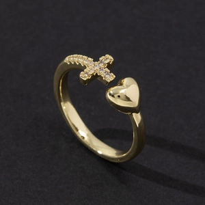Detail of adjustable gold ring with sparkling zircon cross and polished heart motifs