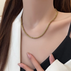 Elegant gold mesh necklace with cylindrical beads shown on a model neck in a close-up view