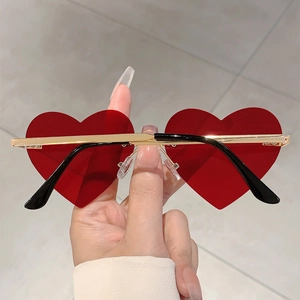 Detail of rimless heart-shaped red sunglasses with elegant gold metal bridge