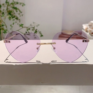 Detail of heart-shaped rimless sunglasses with purple lenses and gold metal temples