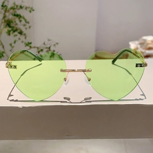 Close-up of heart-shaped rimless sunglasses with green jelly lenses and gold metal frame