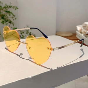 Close-up of rimless heart-shaped sunglasses with yellow lenses and gold metal temples