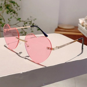 Detail of heart shaped rimless sunglasses with pink jelly lenses and gold metal temples