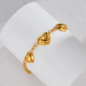 Elegant gold stainless steel bracelet with three hollow heart charms on a white stand
